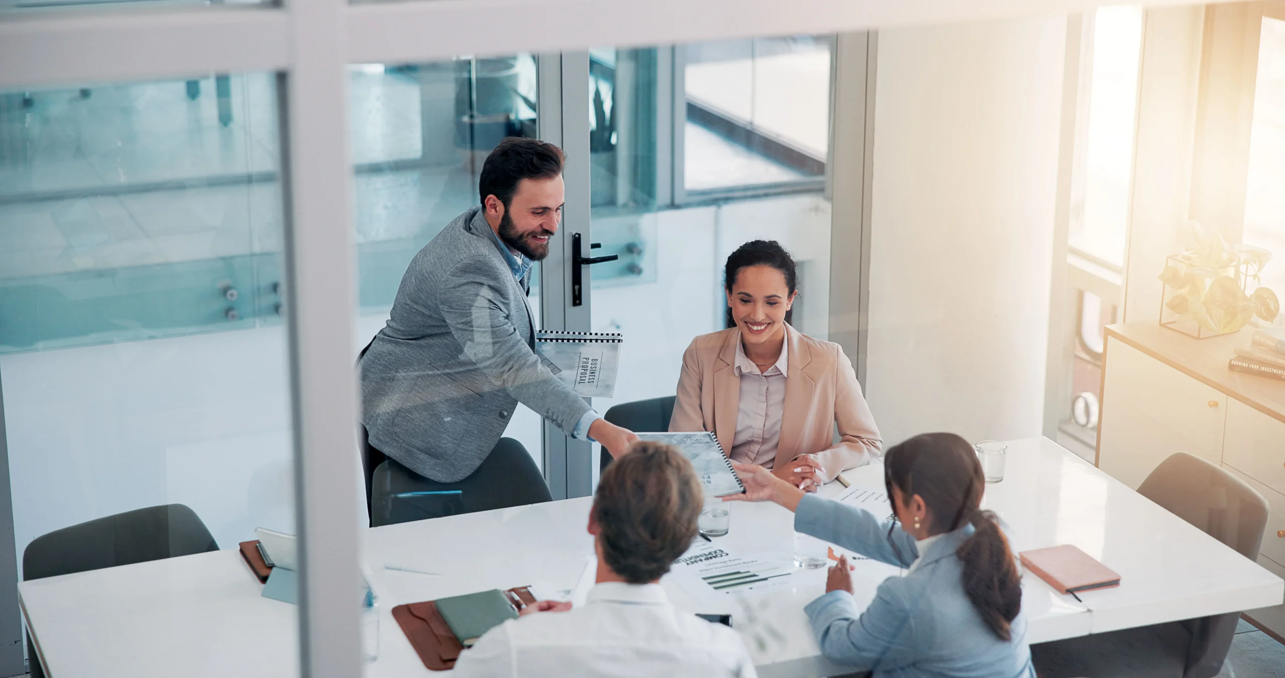 Accounting professionals in a meeting exchanging documents around a conference table in a modern office.