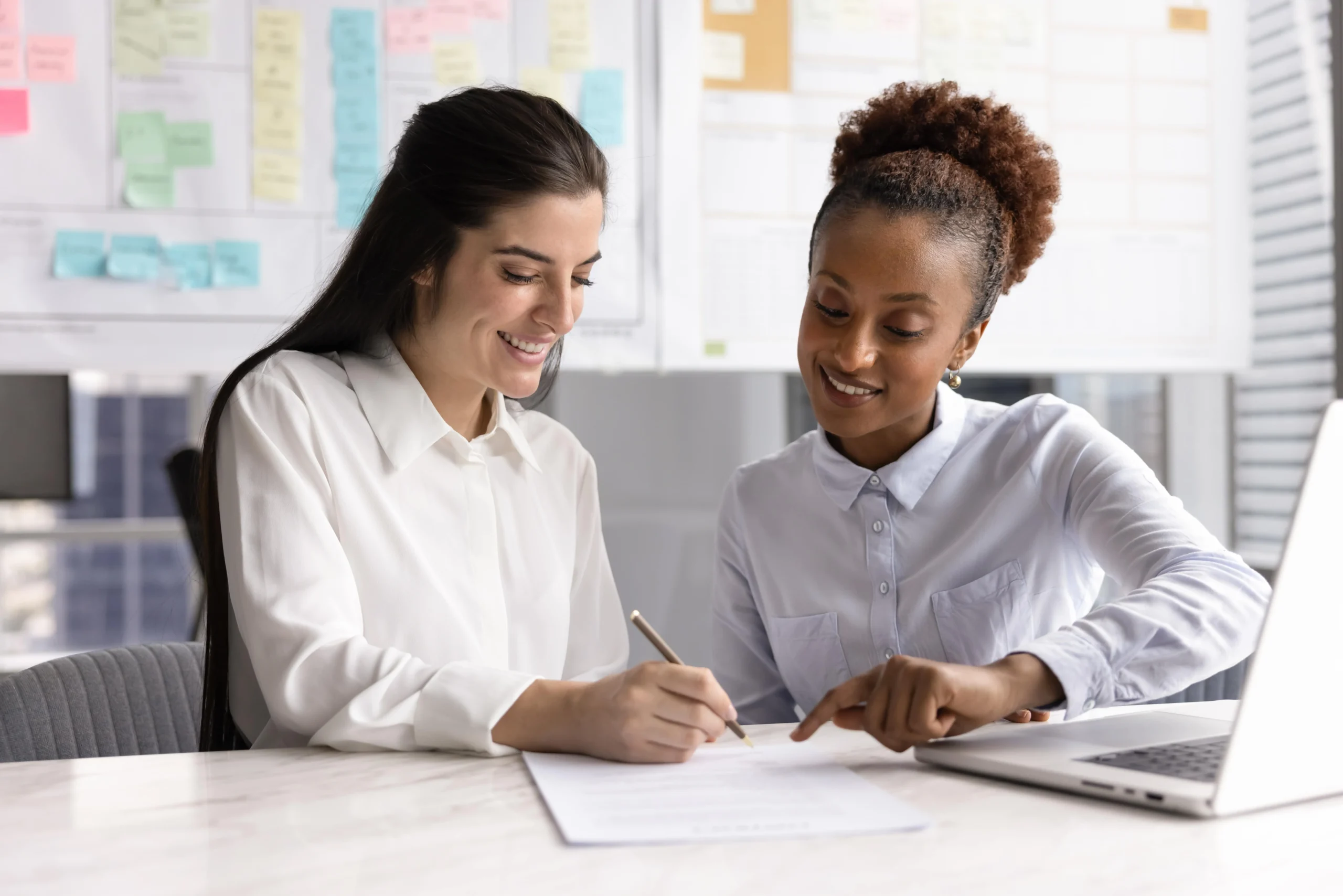 Employee assisting a member with loan or account paperwork at a desk.