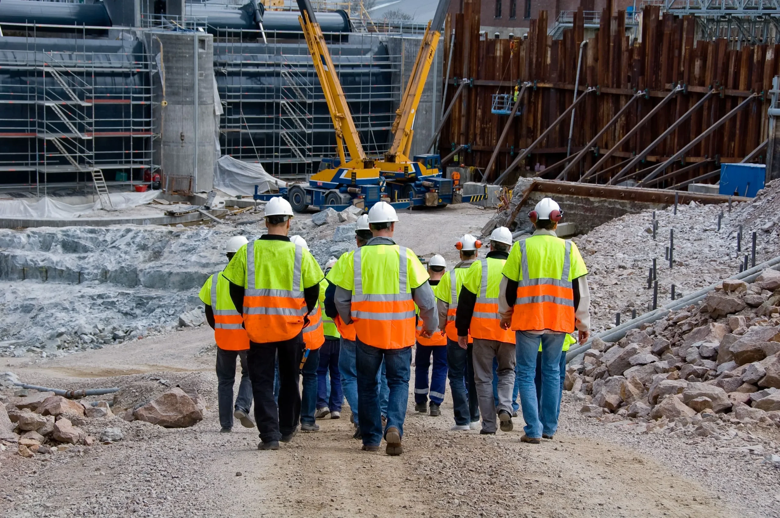 Construction crew wearing safety vests and helmets walking through an active worksite